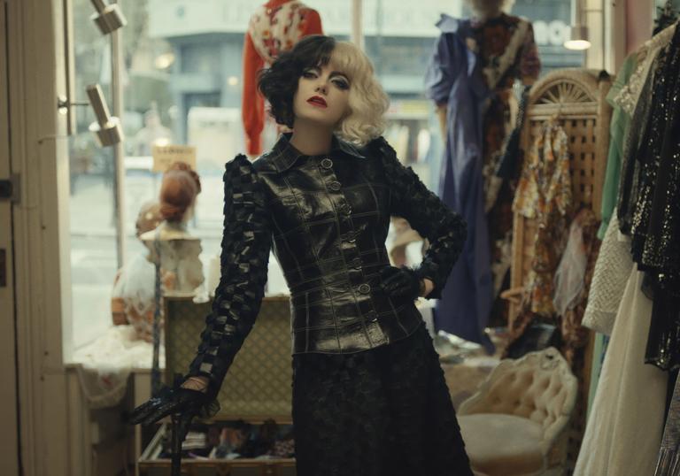 cruella stands in a clothes shop