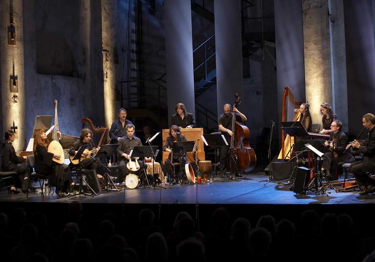 L'Arpeggiata on a lit stage, playing their period instruments