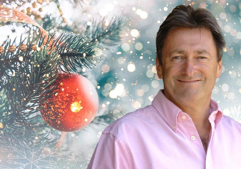 Alan Titchmarsh smiling, with a Christmas tree and bauble behind him