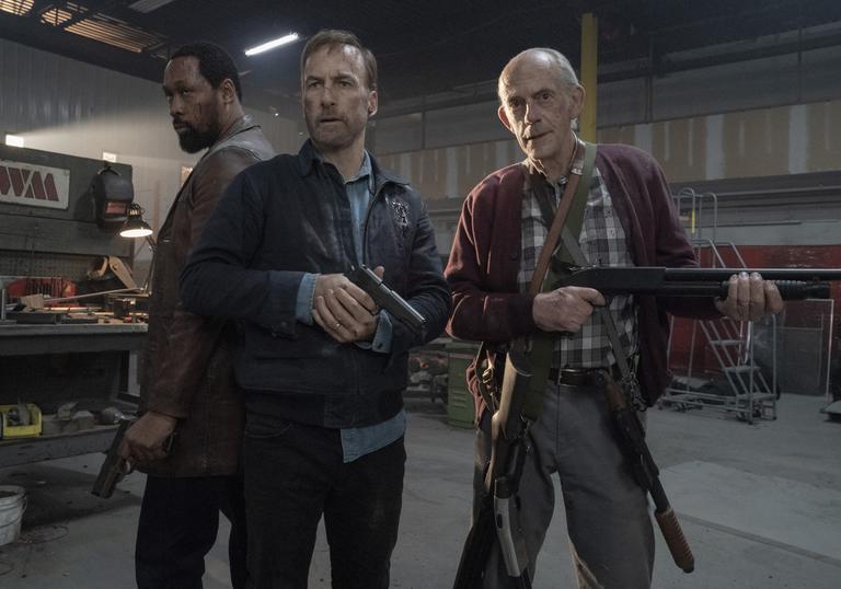 Bob Odenkirk and Christopher Lloyd stand in a striking pose holding guns