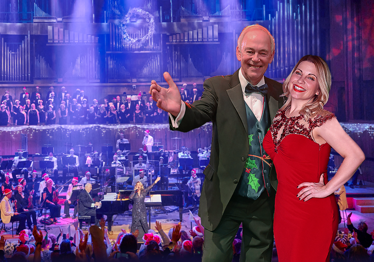 Jonathan Cohen and Louise Dearman smiling in front of an orchestra and choir