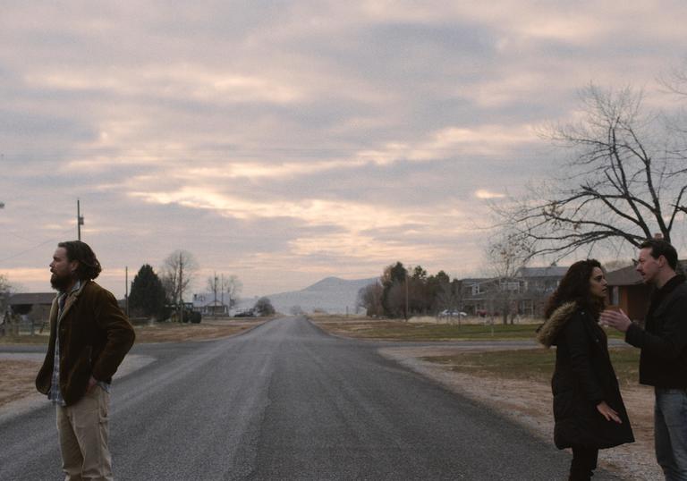 a couple stands at opposite sides of the road looking away from each other