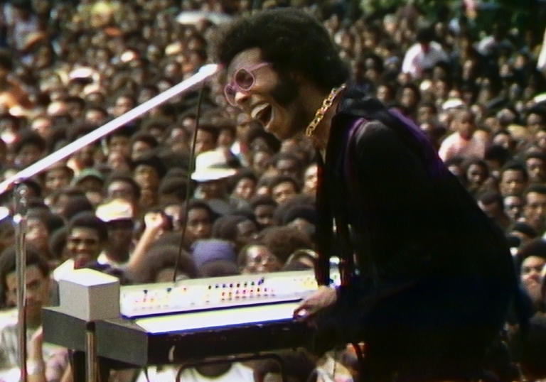 Sly Stone plays for a large crowd of people at the music festival