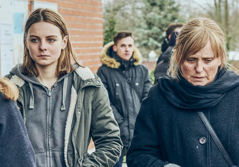 a girl and an older woman stand next to each other looking sad and distressed