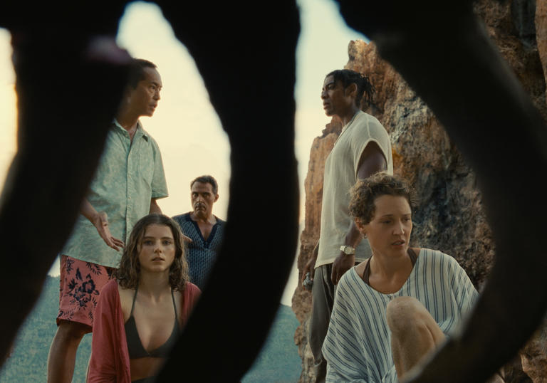 a group of people are on a beach with dark shapes between them