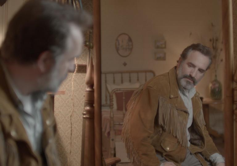 Jean Dujardin looking into a mirror wearing his special jacket