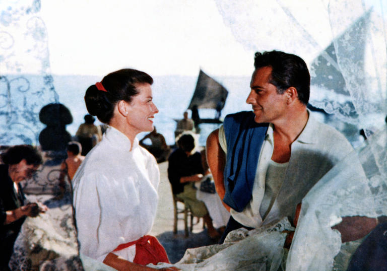 Katharine Hepburn in a white shirt looks at Rossano Brazzi, also in a white shirt, in front of a Venice canal in Summertime by David Lean