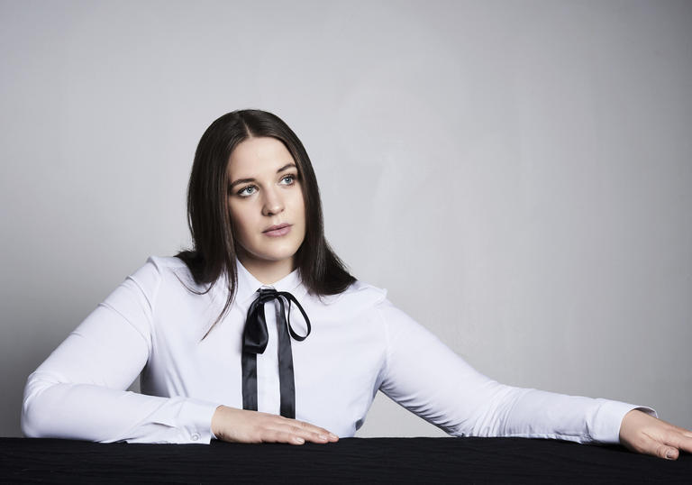 Lise Davidsen sitting at a table with her arms on it, gazing out into the distance