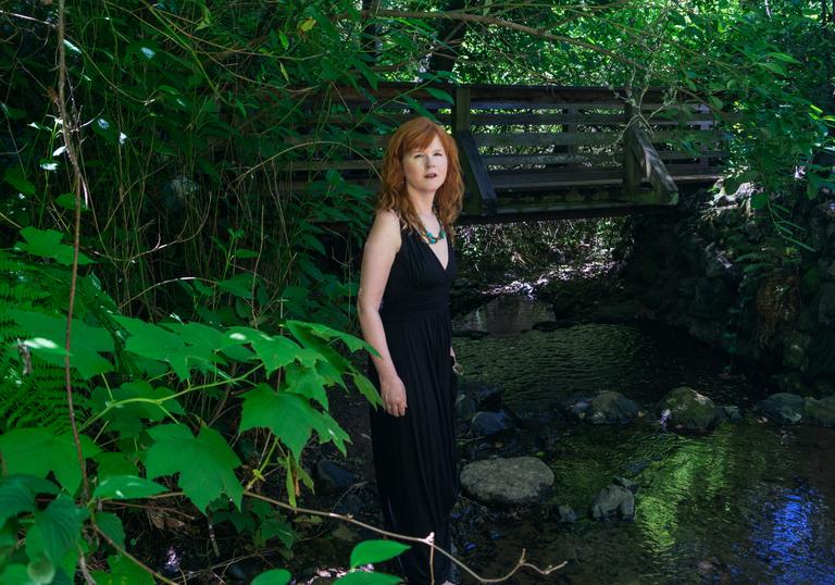 Sarah Cahill standing in a garden in front of a bridge