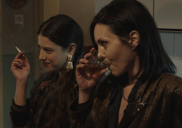 Two women dressed in brown drink liquor in the kitchen in a still from the film Celts (2021)