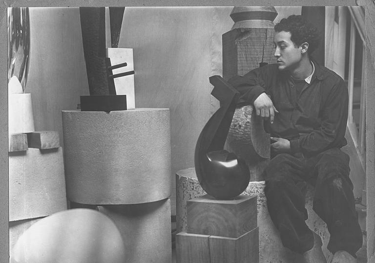 A young Isamu Noguchi in his studio surrounded by sculpture