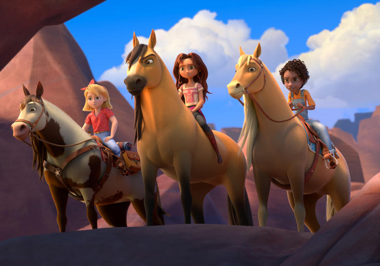 Three girls sit atop horses in a canyon in a still from Spirit Untamed