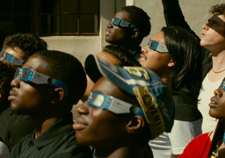 Young people looking at an eclipse, wearing the protective glasses