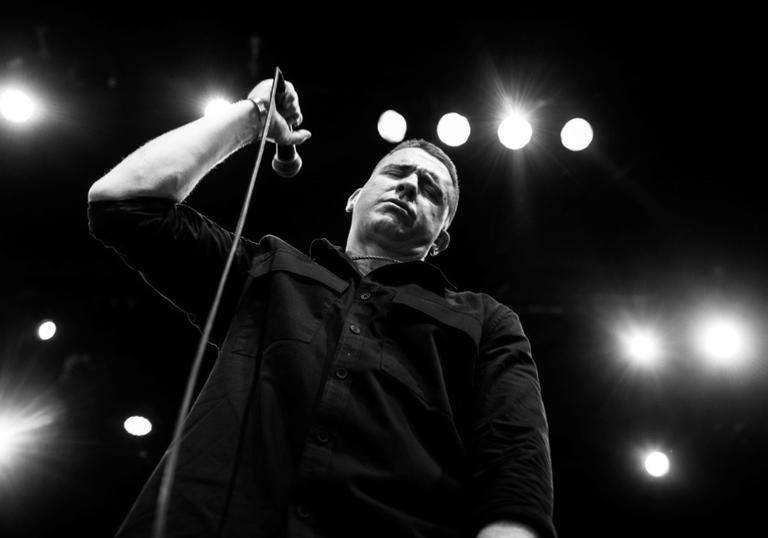 Damien Dempsey in a black and white image shot from below, holding a microphone