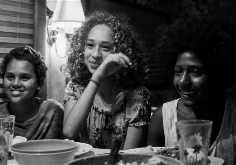 Nico Rockwell, Lana Rockwell and Jabari Watkins sit next to each other at a dinner table in a b&w image from Sweet Thing