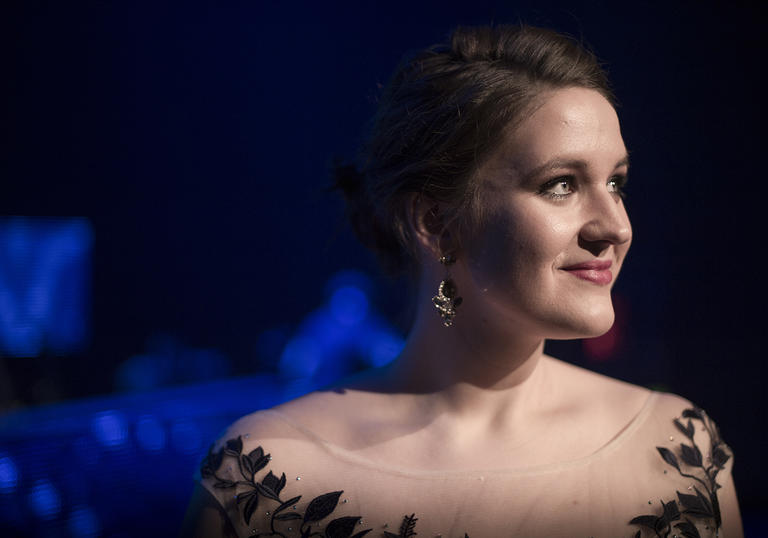 Lise Davidsen looking to her left, smiling, in front of a blue-lit backdrop