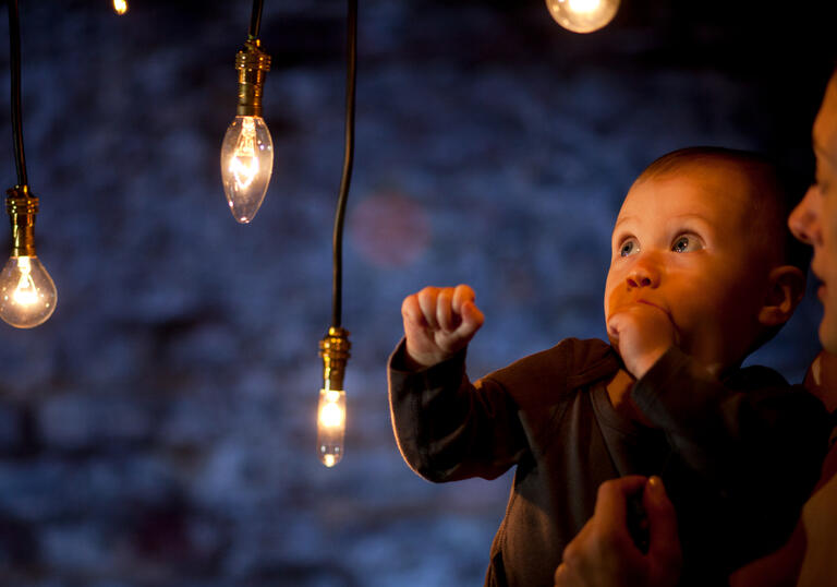 Baby looking up at an installation of hanging lights