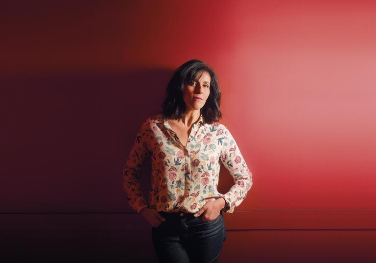 a colour photo of Souad Massi against a red backdrop