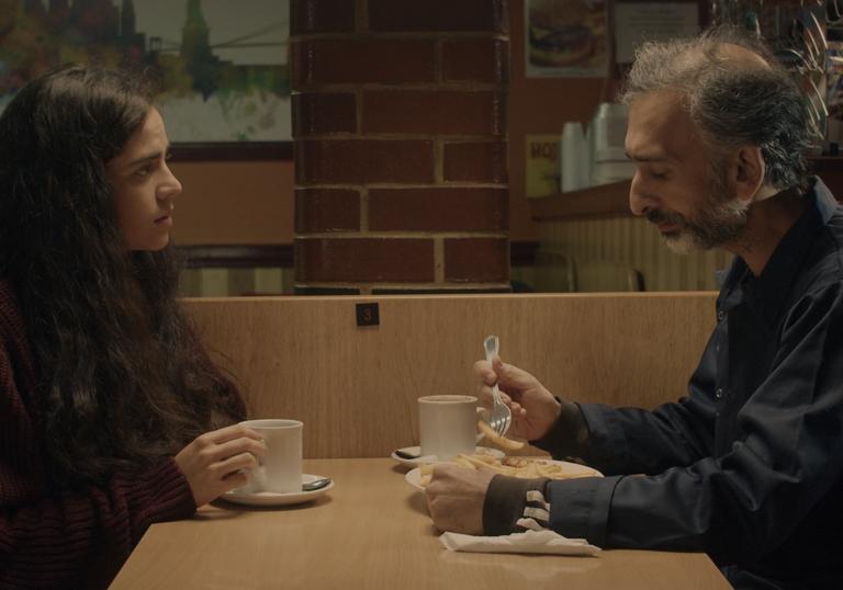 A photographic still of a young woman and an older man having a coffee from Without Warning