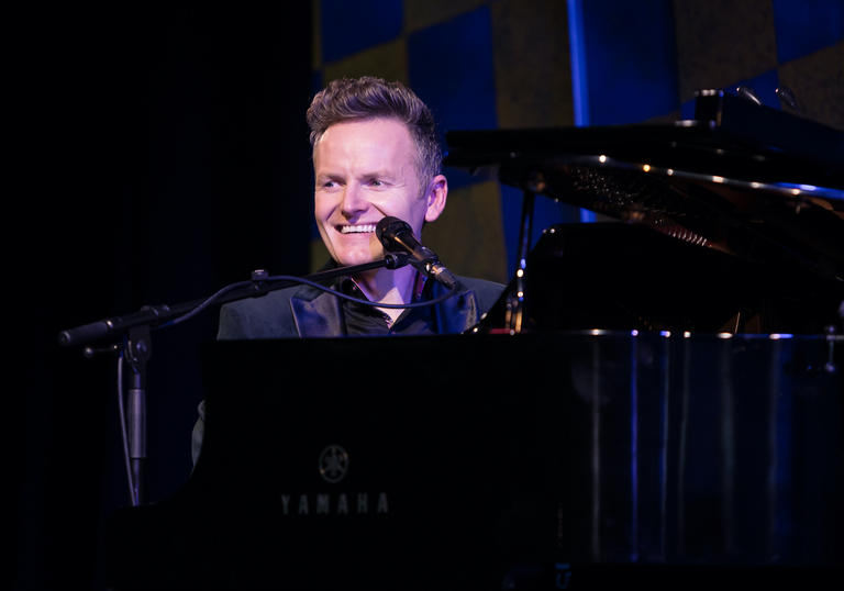 Joe Stilgoe smiling behind a grand piano