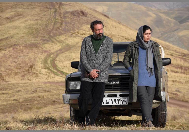 Man and Woman leaning on a car in deserted area