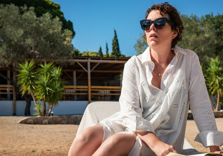 Olivia Coleman as Leda, sitting on a sun lounger looking into the distance