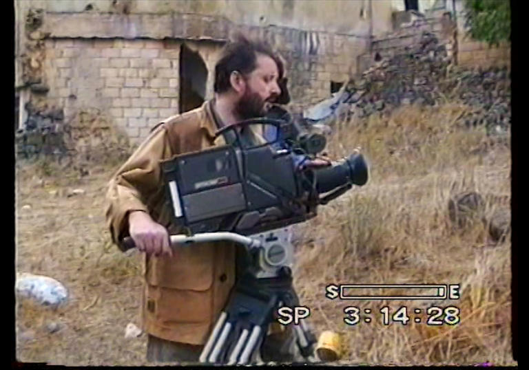 Still image of man directing a camera