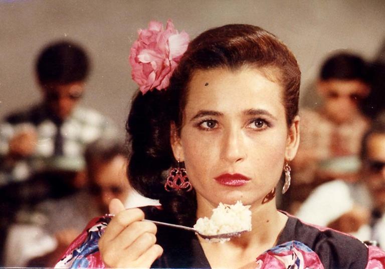 Still image of a woman ready to eat a large mouthful of pudding from a spoon