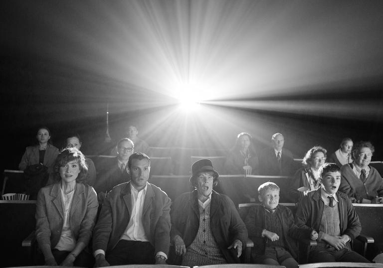 Black and white image of the family from Belfast, seated watching a film