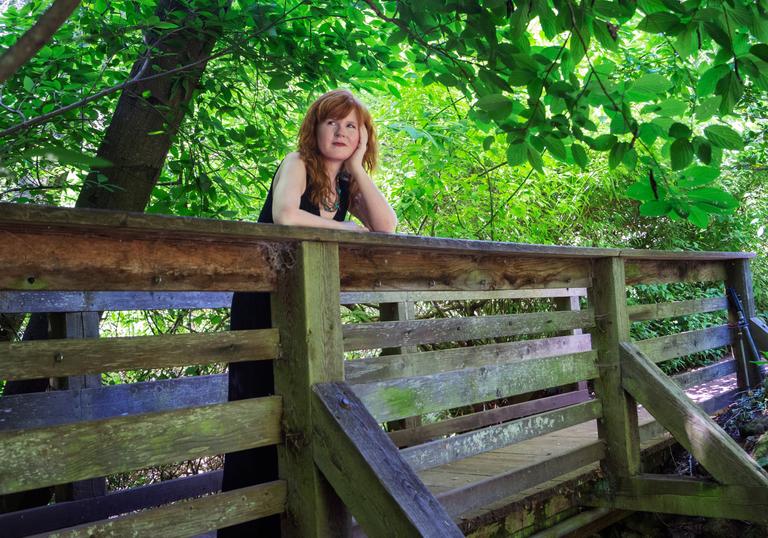 Sarah Cahill standing on a wooden bridge surrounded by trees