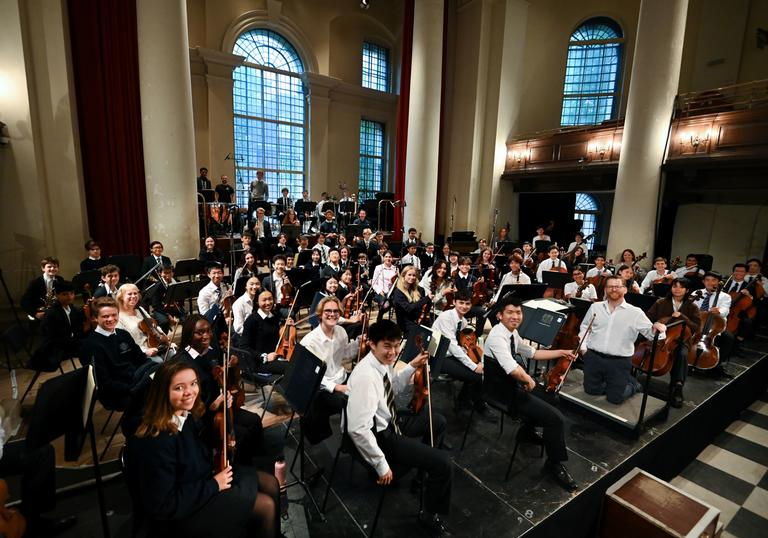 Westminster School Symphony Orchestra smiling at the camera holding their instruments