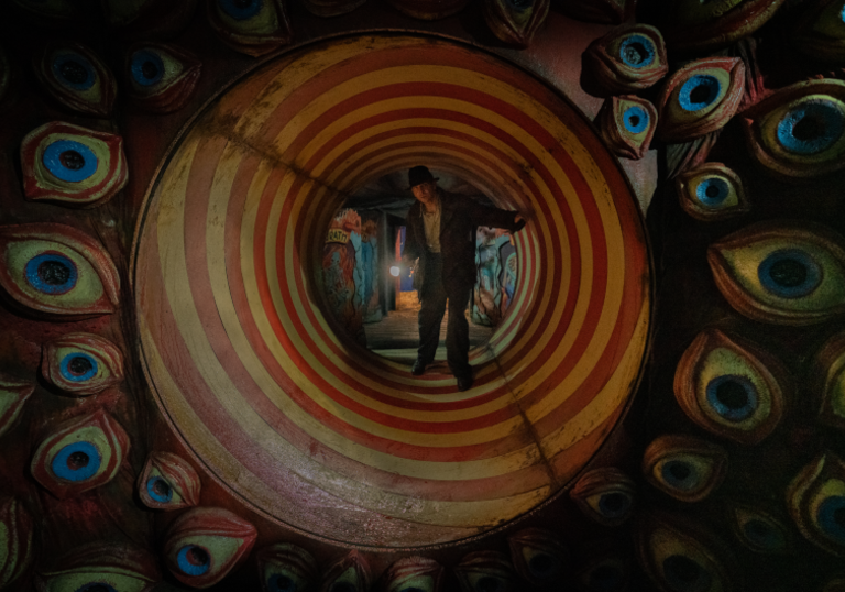 Bradley Cooper's character in Nightmare Alley in a carnival tunnel striped with red and white