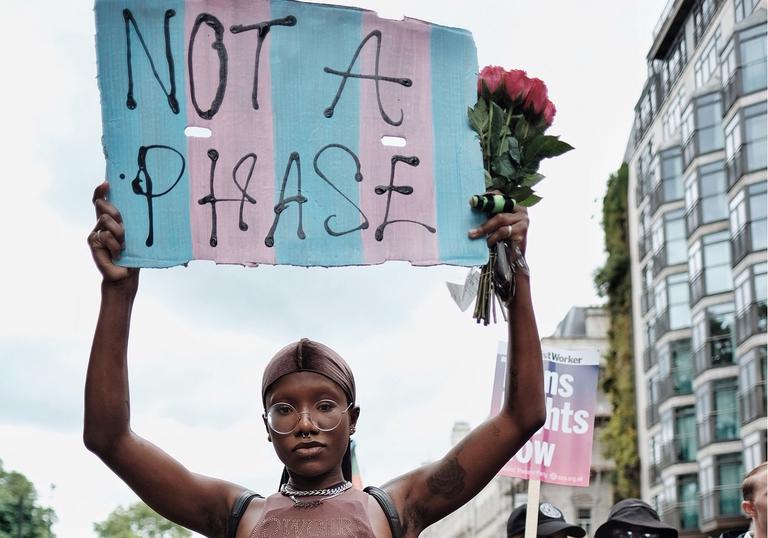 A person at Trans Pride holding a sign which says 'Not A Phase'