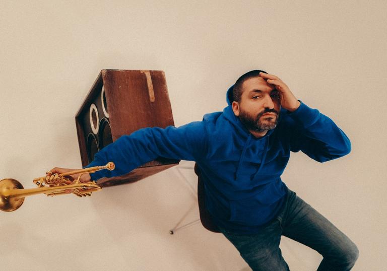 an photo of Ibrahim Maalouf holding a trumpet next to an amp taken from above