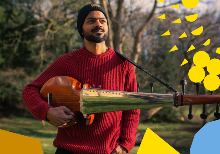 Soumik Datta standing in a park holding a sarod