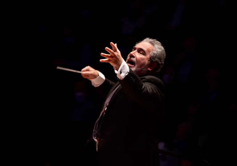 A spotlight shines on Carlo Rizzi as he conducts