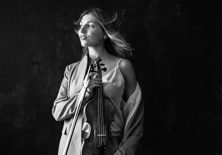 Black and white photo of Diana Tishchenko holding her violin