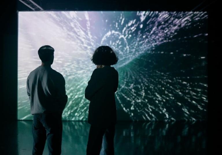 two people looking at a large illuminated screen