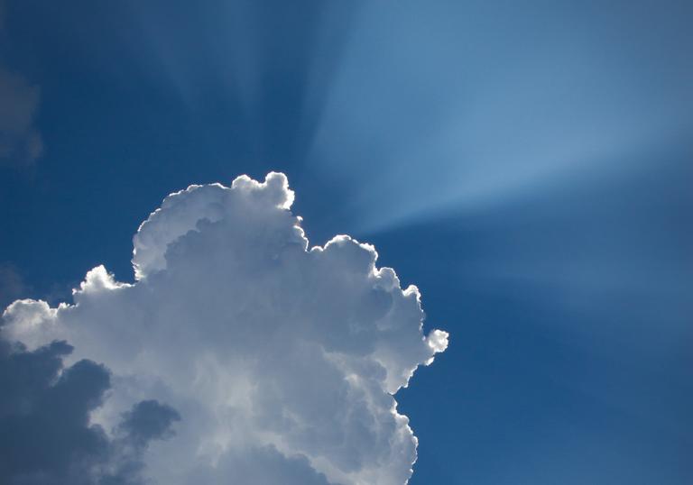 Photo of the sun's rays shining from behind a cloud
