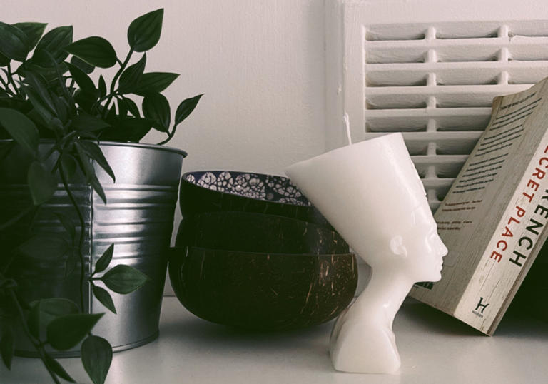 image of a white candle in the shape of egyptian head next to a pot plant