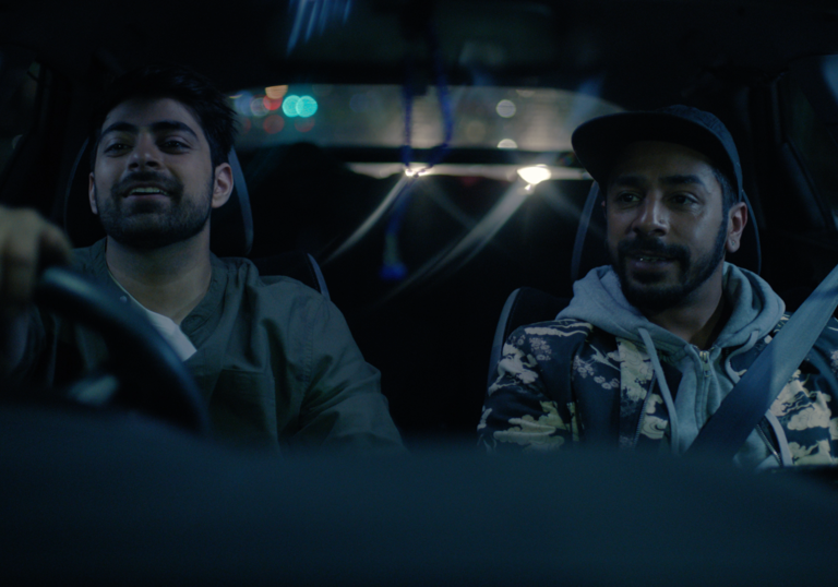 A still from Tasbeeh, two young men at the wheel and in the passenger seat of a car