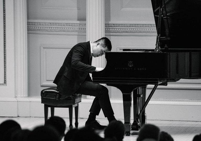 Black and white photo of Lionel Yu playing a grand piano