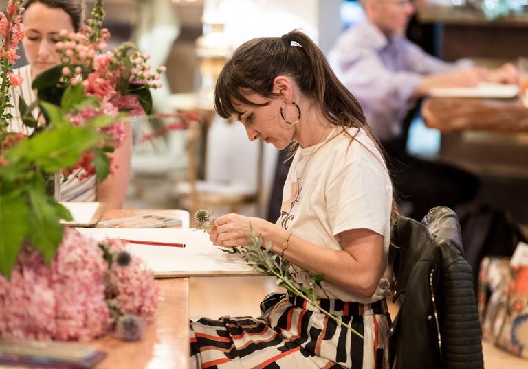 Woman drawing a vase of pink and green flowers