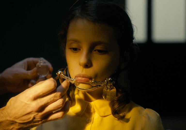 A young girl wears unusual braces in a still from Earwig