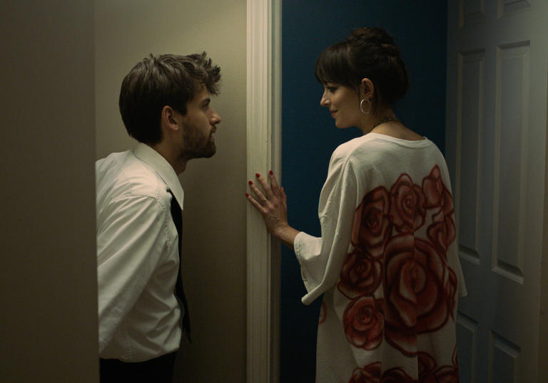 Cooper Raiff and Dakota Johnson look at each other in front of a doorway