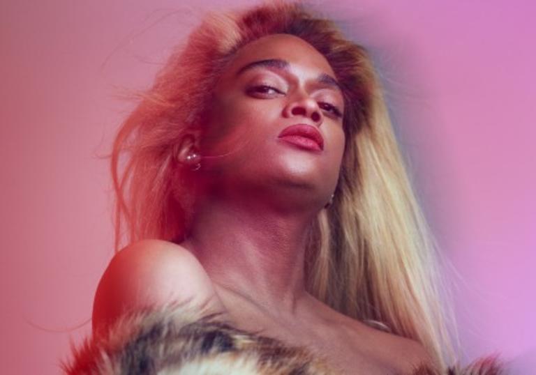 Artistic portrait of Lotic in a pink hue with dyed blonde hair and faux fur statement coat