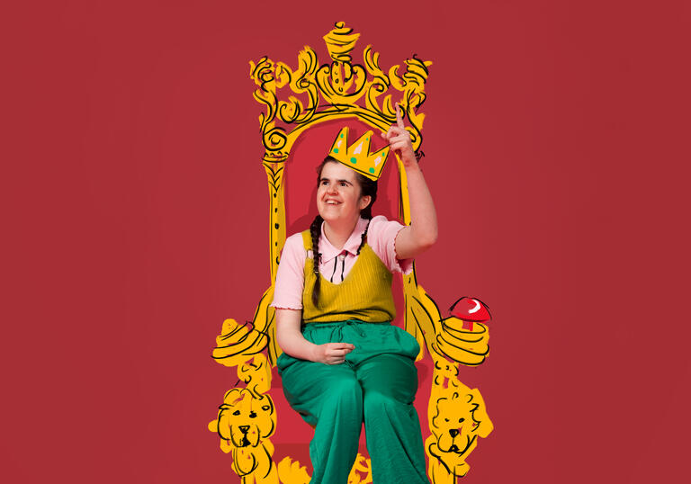 Rachel, a learning disabled artist, sits on a throne wearing a gold crown. There is a pink background behind her.