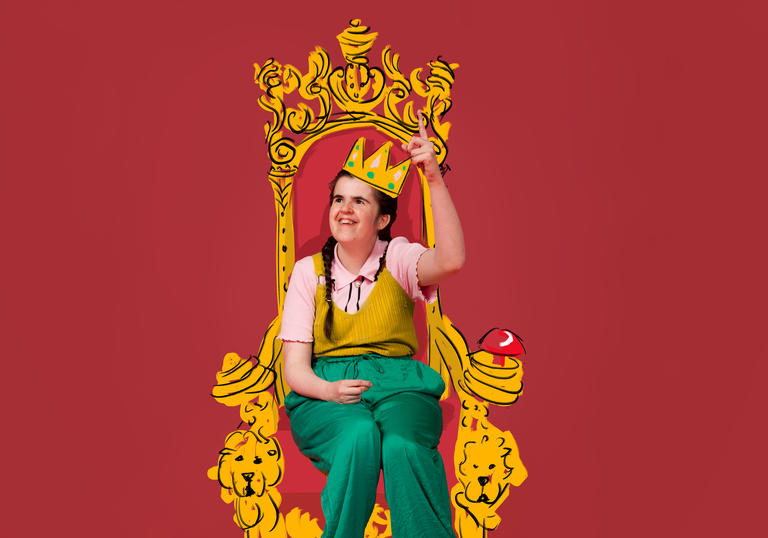 Rachel, a learning disabled artist, sits on a throne wearing a gold crown. There is a pink background behind her.