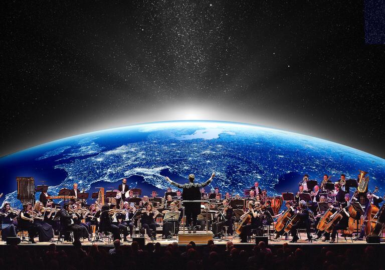 The London Concert Orchestra playing in front of an image of the Earth as seen from space