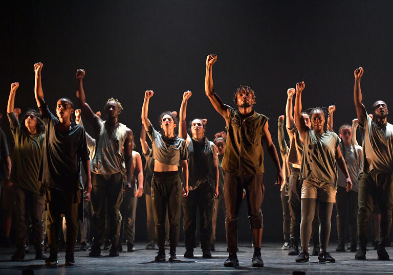 A group of people stand together with arms in the air 